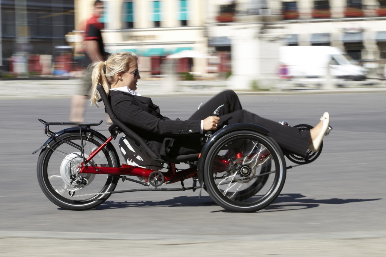 Woman in business suit riding an eltric recumbent three wheeled ebike